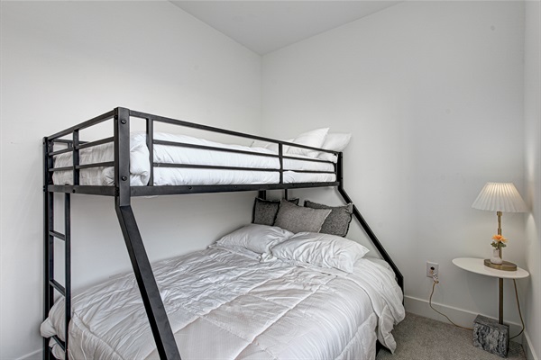 Relax in the serene bedroom featuring a comfortable king-size bed, soft linens, and cozy pillows. Includes nightstands, lamps, walk-in closet, and full-length mirror for added comfort.