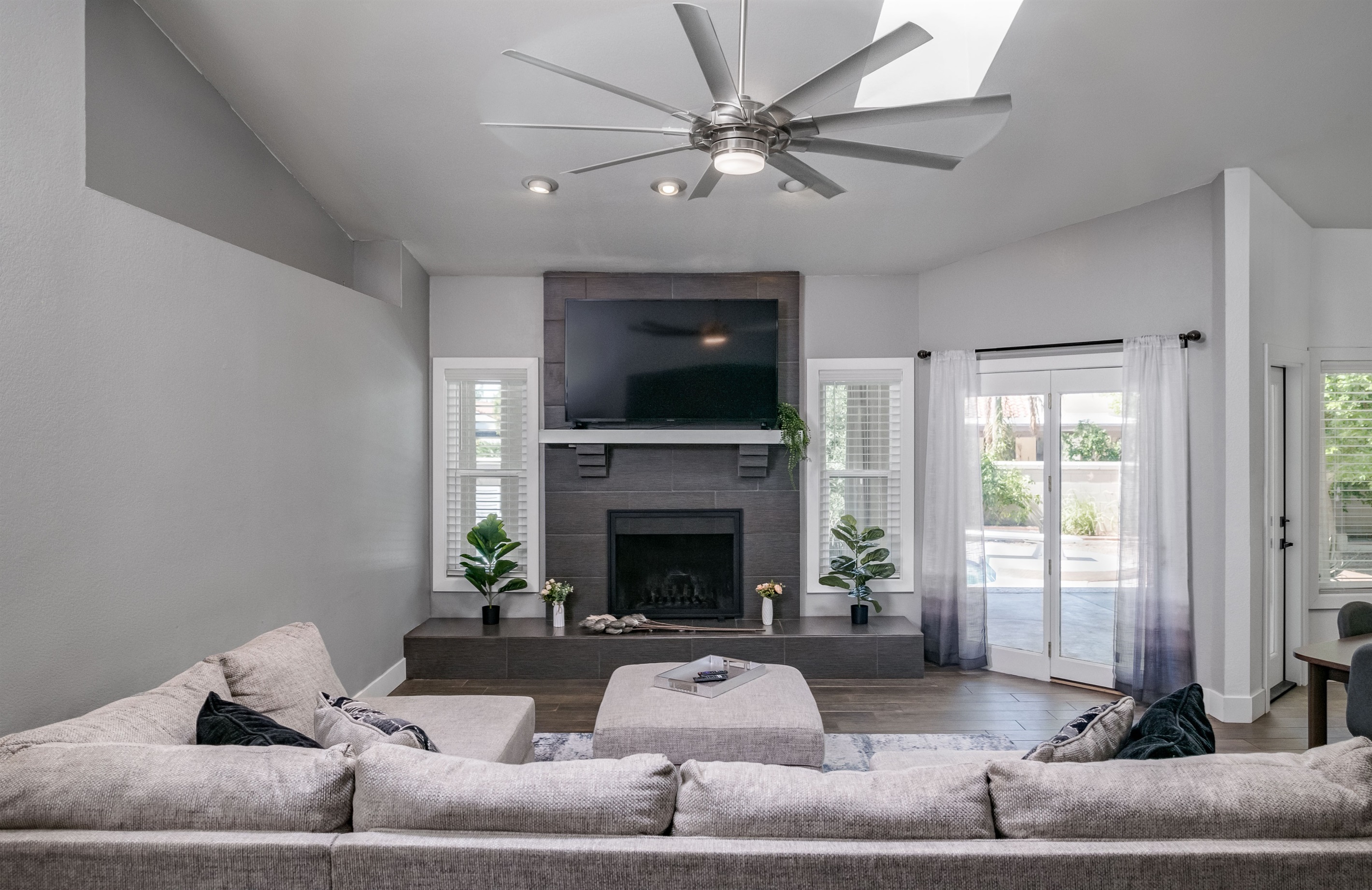 Spacious and sunlit, this living room features soaring ceilings, a cozy fireplace, and plenty of room for movie nights or game-day gatherings.