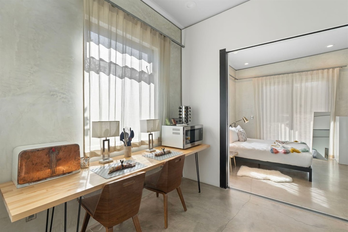 Bright workspace area with dual seating, natural light, and direct access to the bedroom.