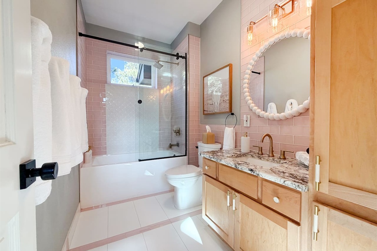 Bright and charming custom bathroom with tub, shower, plush towels, and thoughtful touches for a cozy, inviting experience.