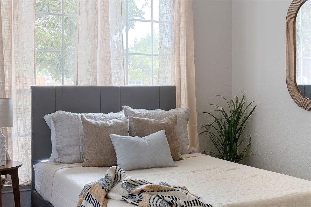 Inviting bedroom featuring two cozy double beds, adorned with plush pillows. A stylish wall mirror adds a touch of decor, complemented by a spacious closet for organization. Natural light streams through the window creating a tranquil atmosphere.