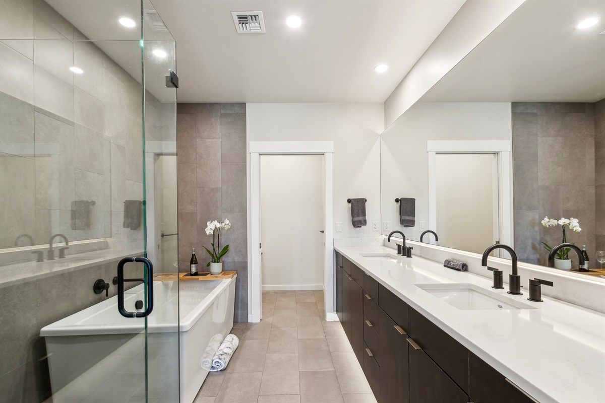 The master suite bathroom with double vanity, giant soaker tub, private toilet, and a tile shower.