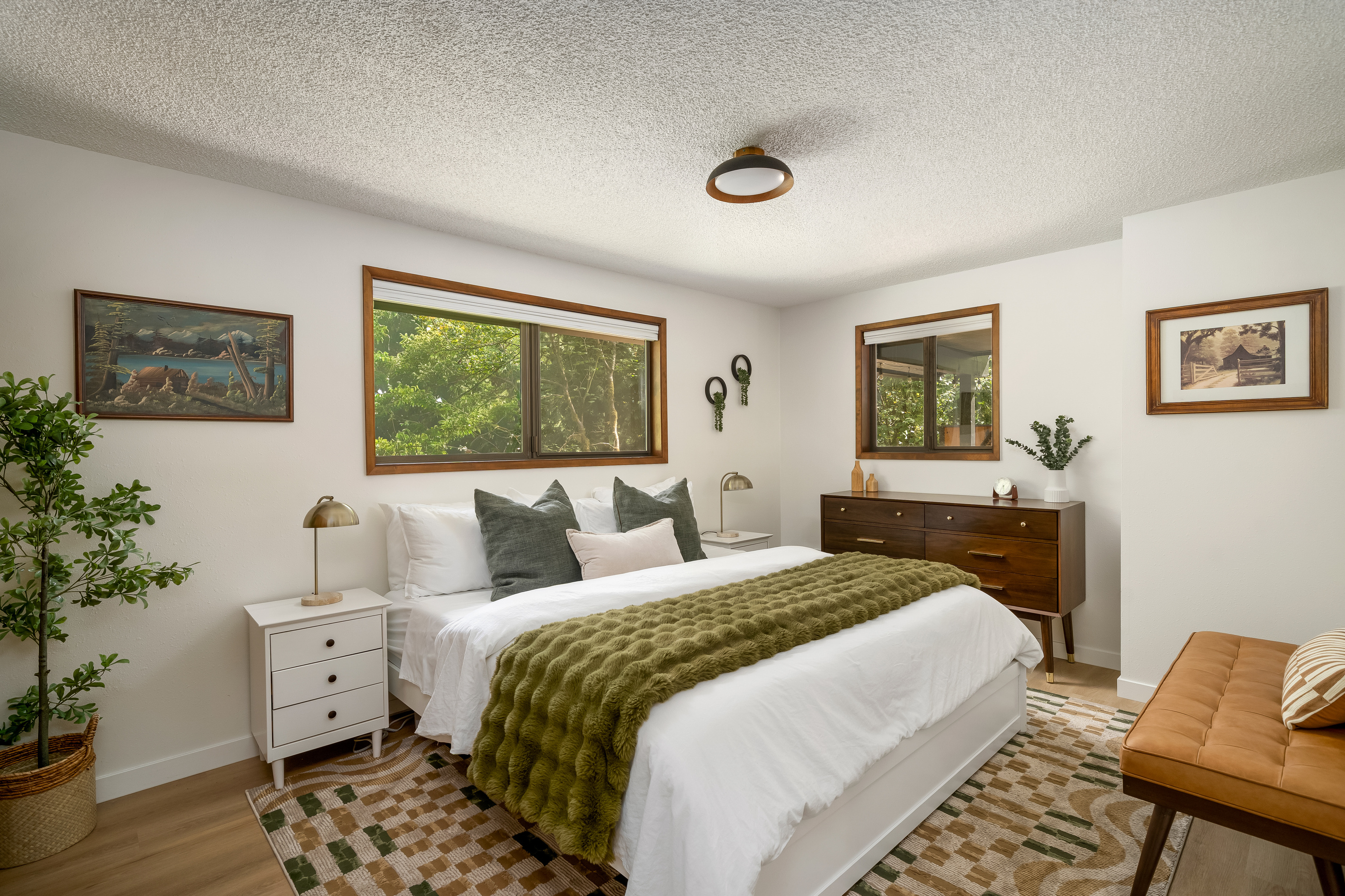 Vintage art, warm wood tones, and forest views — this king bedroom has real character.