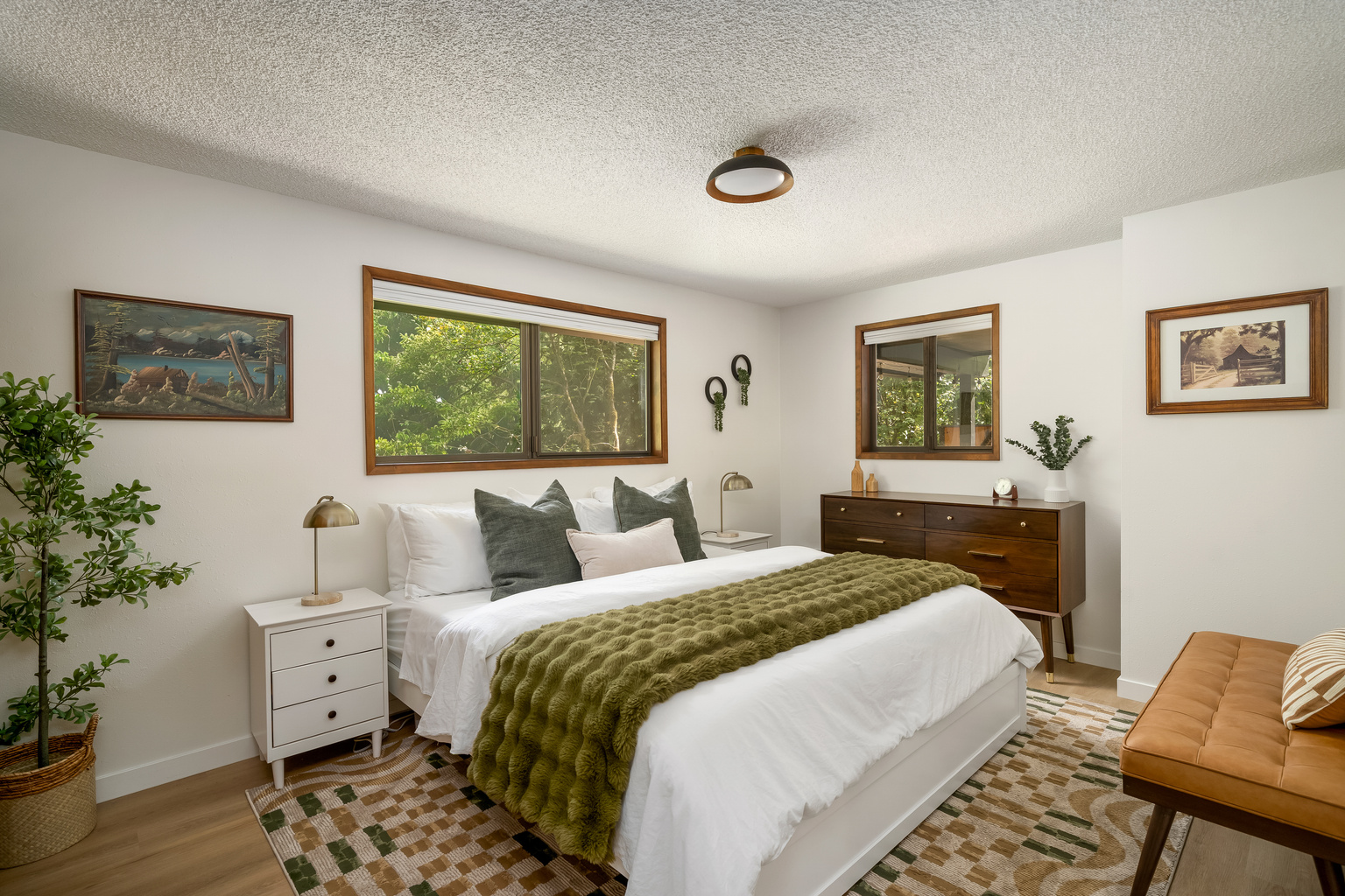 Vintage art, warm wood tones, and forest views — this king bedroom has real character.