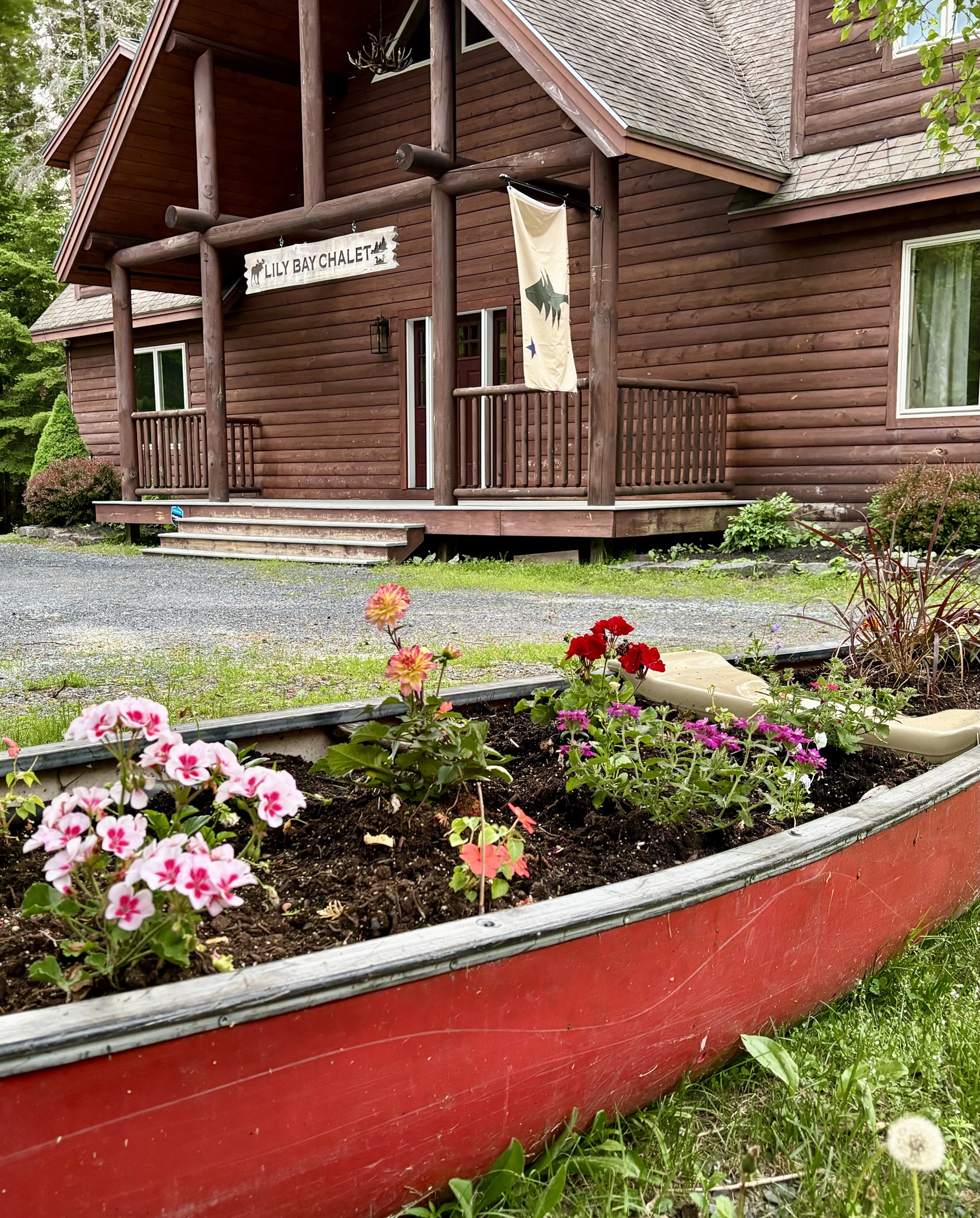 Front of the chalet with canoe flower garden and custom hand made sign welcoming you to your relaxing getaway.