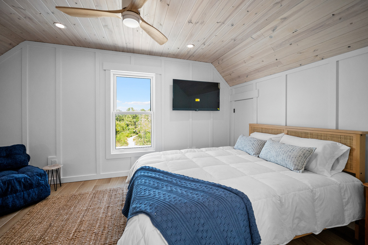 Upstairs queen bedroom with natural light, TV and a tucked-away sleeping nook.