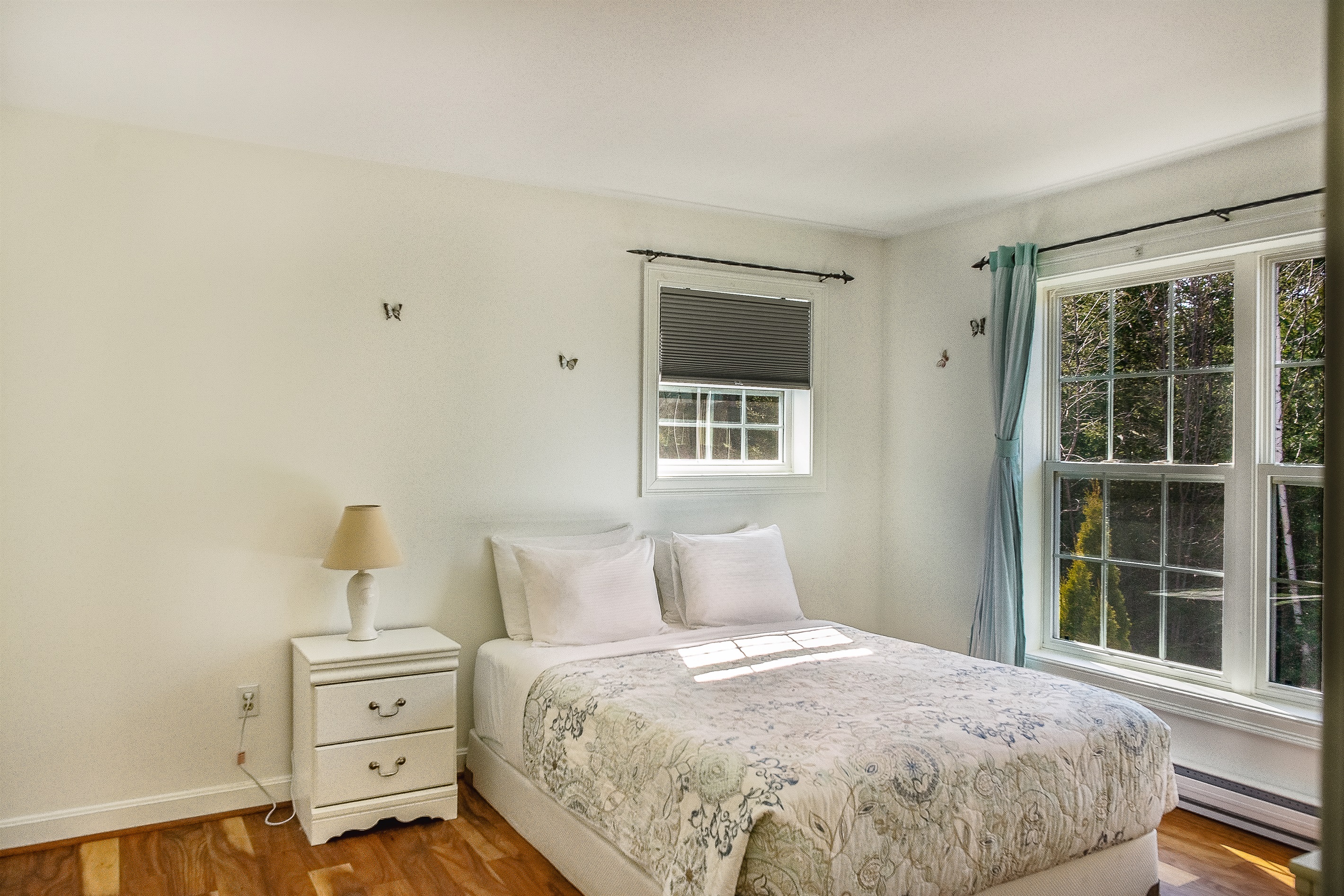The "Butterfly Room" features a comfortable queen bed and large windows overlooking the backyard and deck. With blackout blinds and curtains, it’s a peaceful haven designed for a restful night’s sleep after exploring Southwest Harbor.