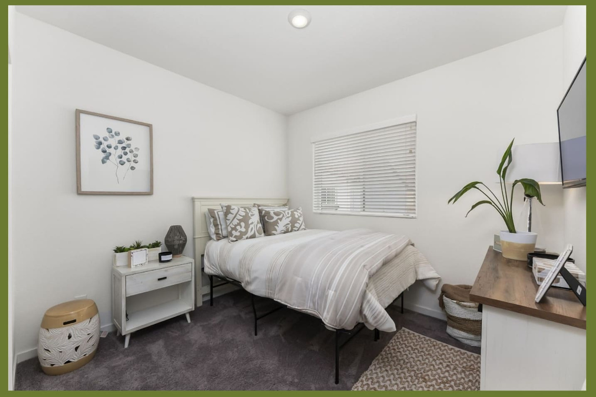 Guest bedroom with a comfortable queen bed, wall-mounted TV, nightstand, and a clean setup for a restful stay.