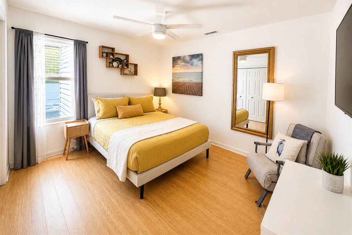 Yellow room with desk, television and queen size bed 