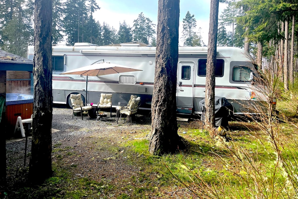 From the forest, showing the Hot Tub, privacy fence and fire pit seating area