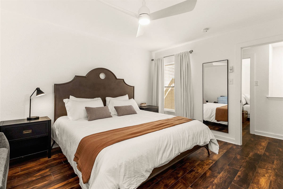 King bedroom with hardwood-style floors and fresh linens