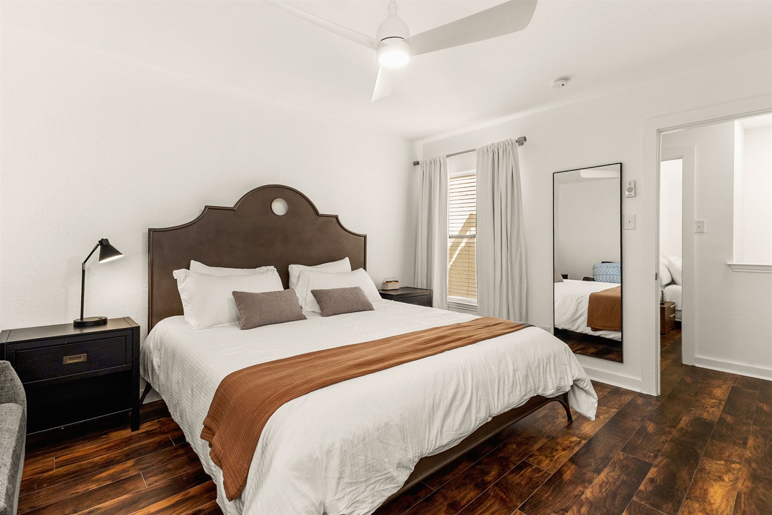 King bedroom with hardwood-style floors and fresh linens
