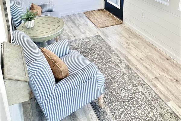 Enjoy a quiet moment in our bright sunroom, featuring comfortable blue-and-white striped armchairs and a classic pedestal side table. This cozy nook is perfect for morning coffee or getting lost in a good book.