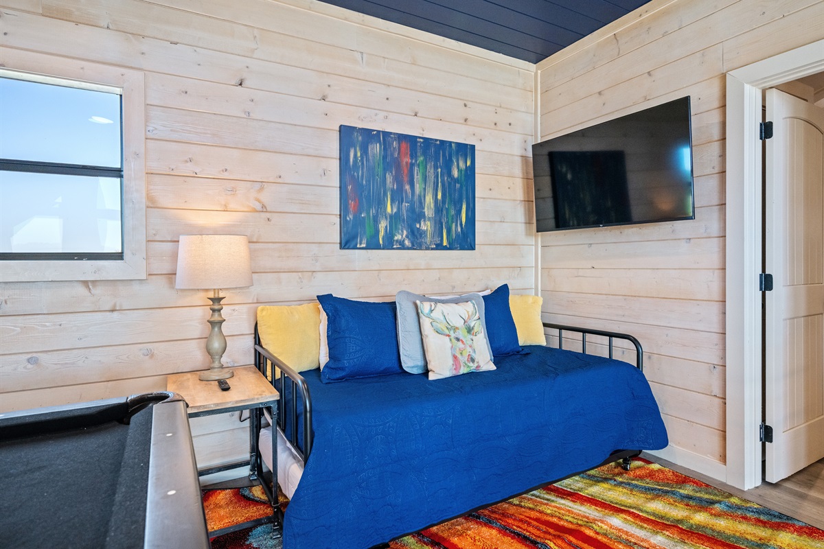 Loft game room with Trundle bed, TV, and extra bedding.