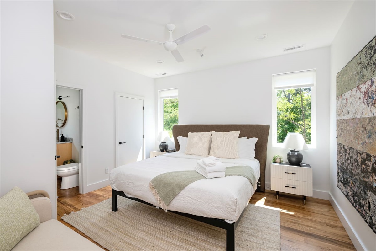 Upstairs primary bedroom suite with king bed, settee and views of woods and backyard