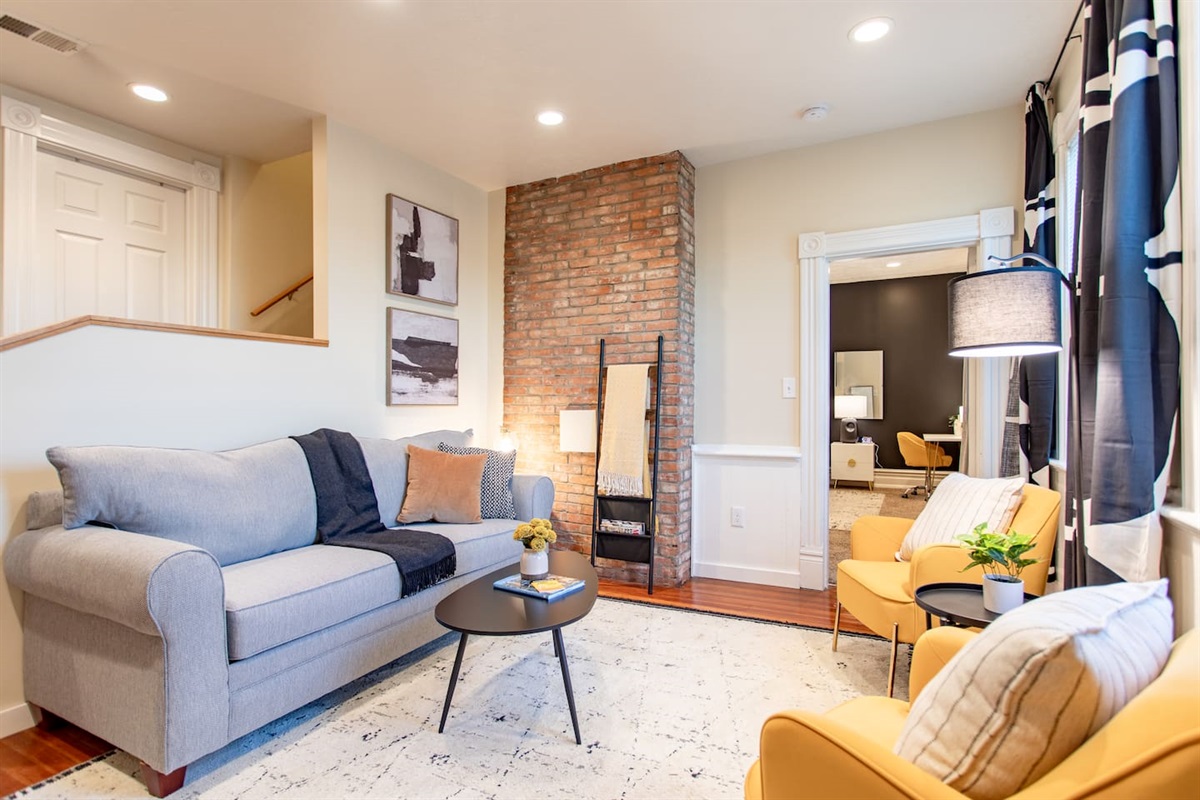 A warm and inviting living area featuring a plush sofa, soft lighting, and a dedicated workspace with a sleek desk and comfortable chair, perfect for productivity and relaxation.