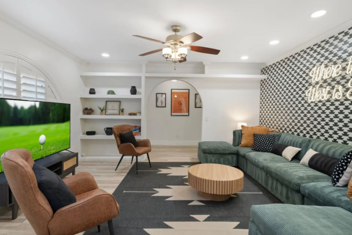 Sink into the deep green sectional and let the evening unwind. Desert-inspired art peeks through the archway, a bold houndstooth wall sets the mood, and the neon glow overhead makes it clear this room was made for gathering