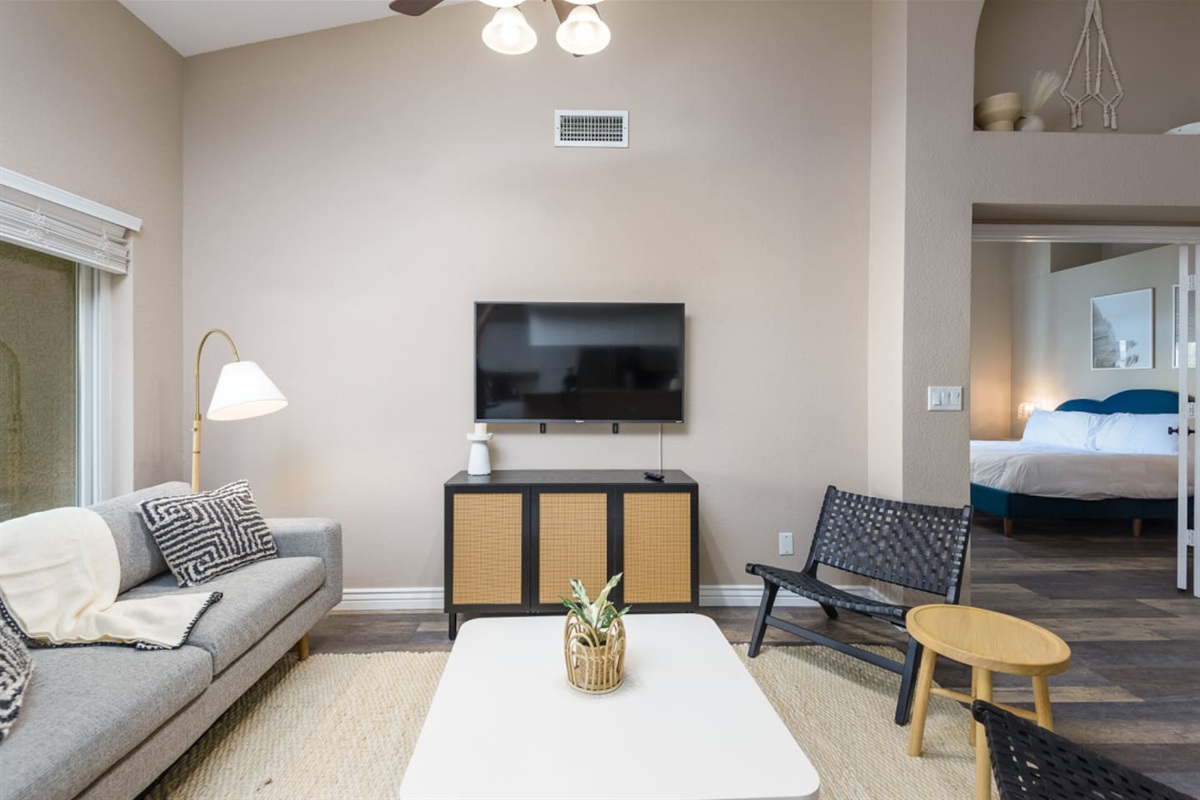 Sitting area with wall-mounted TV, comfortable seating, ceiling fan, and patio door access for relaxed downtime.
