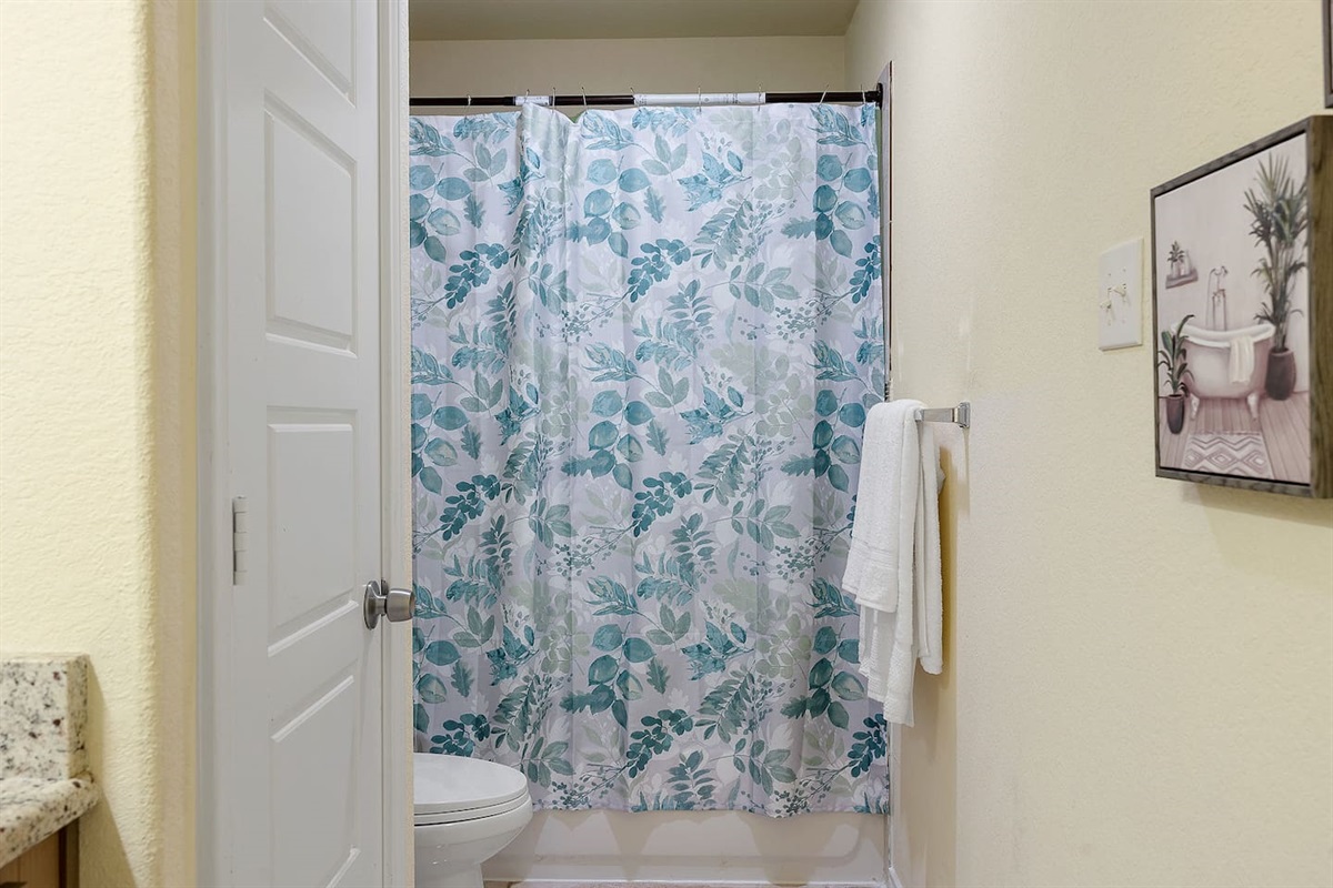 Discover a bright and clean bathroom with stylish wall art and a fresh shower curtain.