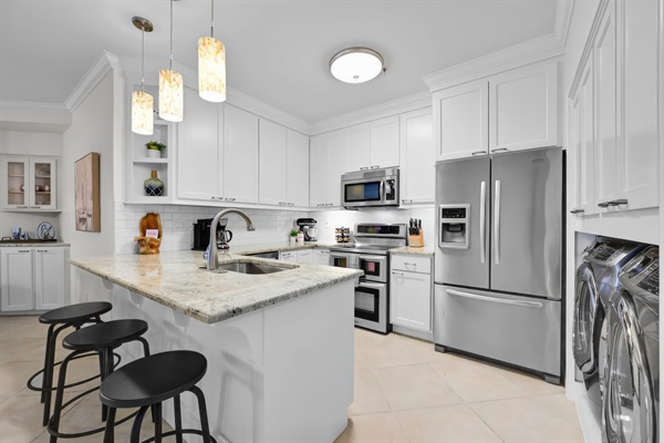 Modern full kitchen with stainless appliances, white cabinetry, and everything needed for easy vacation meals.