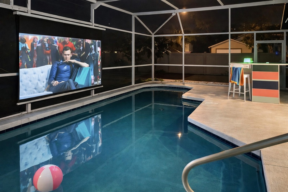 Enjoy a modern poolside bar and dining area under a screened enclosure.