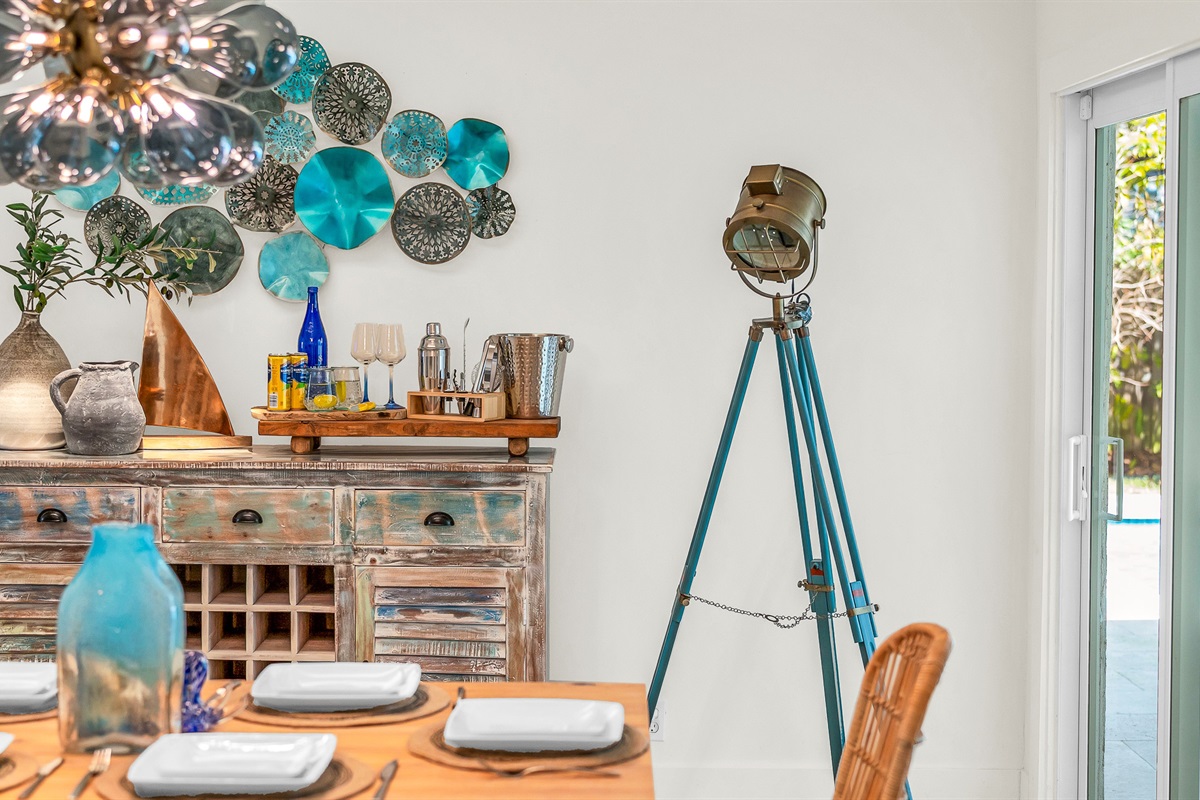 Rustic wood dining accented by chic rattan chairs and a chandelier. Enjoy meals and entertaining in luxurious coastal style.