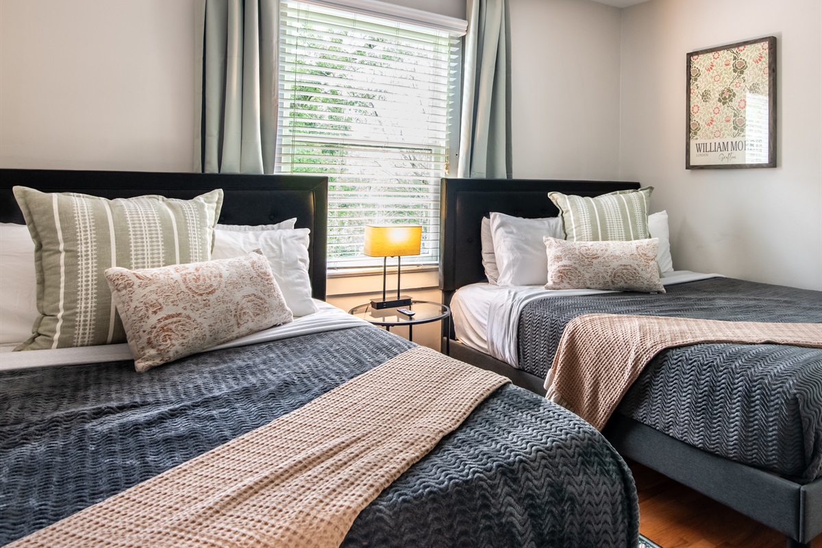 Stylish twin bedroom with natural light, soft bedding, and modern decor — great for kids or friends