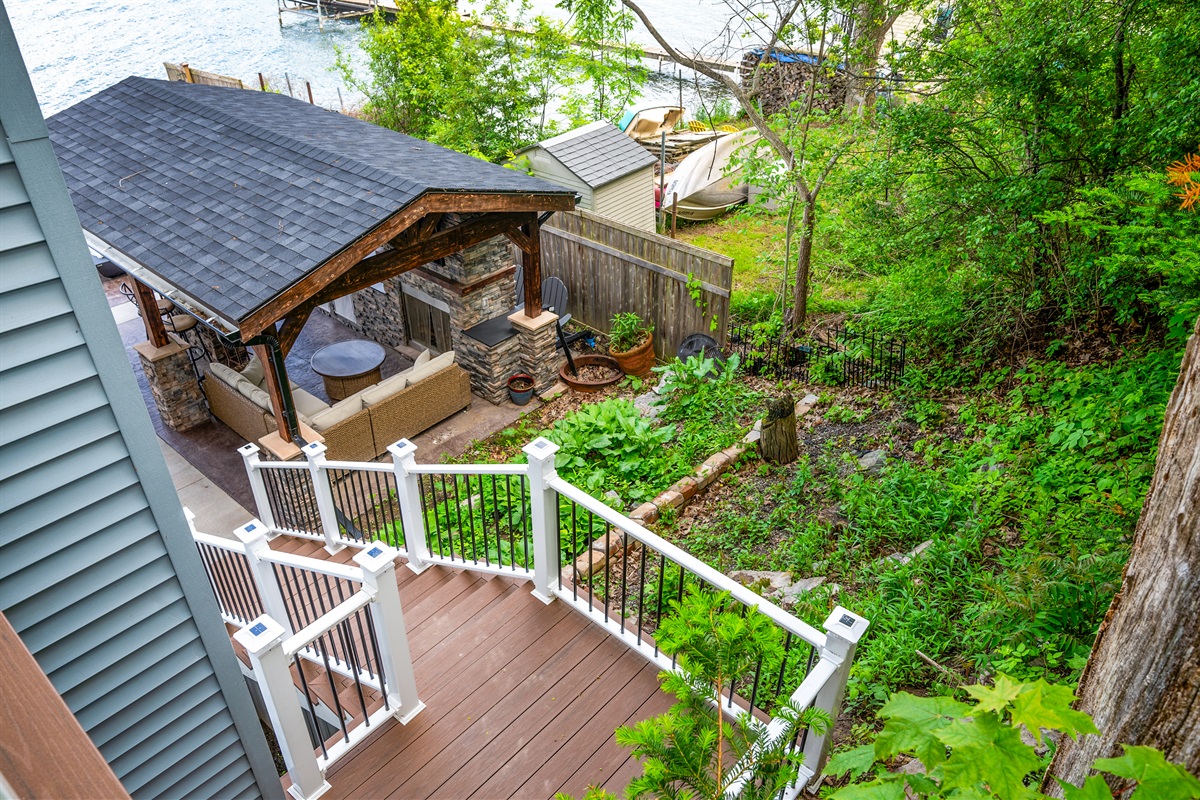 Relax lakeside in this beautiful backyard retreat featuring a covered patio, cozy seating, and lush greenery. 🍃🔥🏡