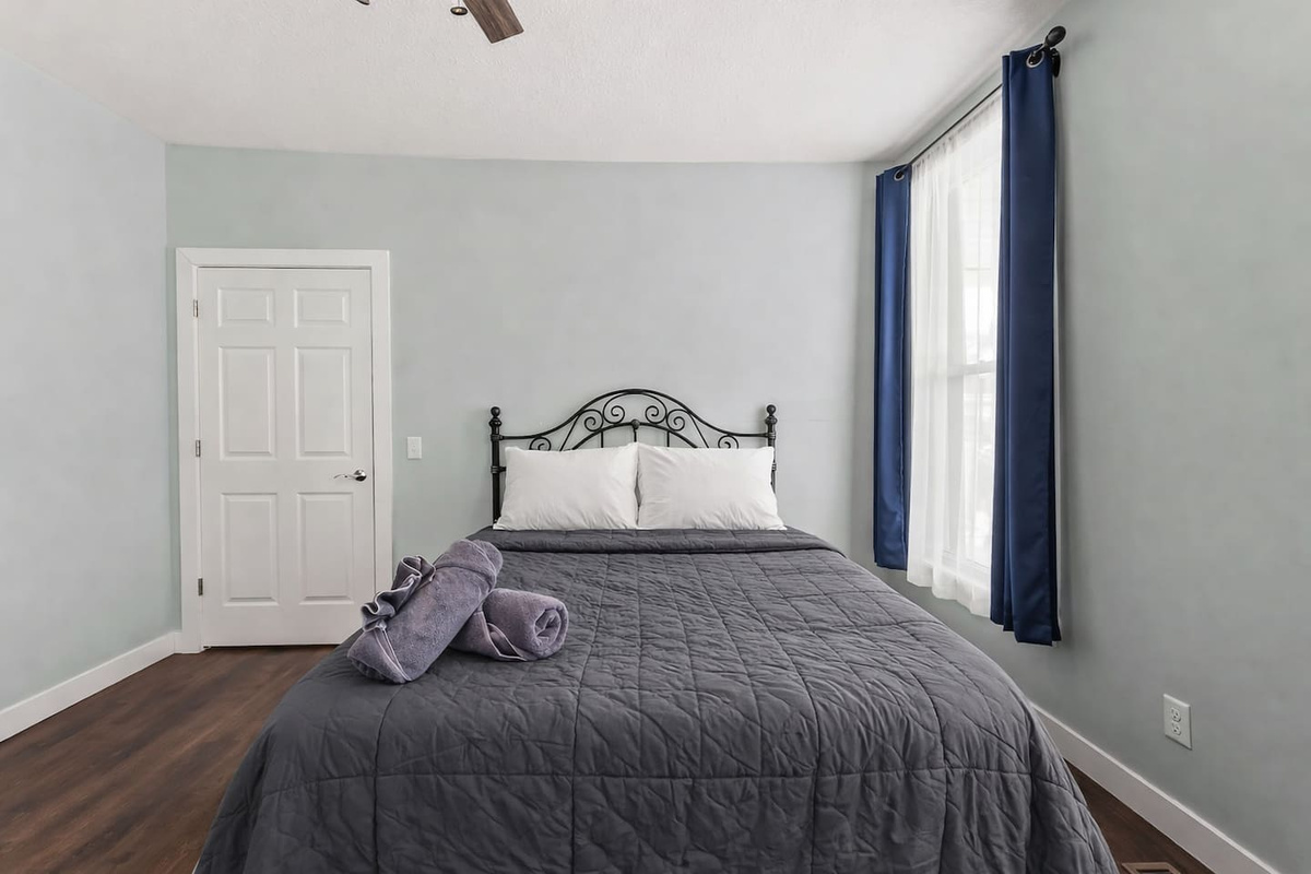 Queen bed dressed in fresh linens, paired with a ceiling fan and classic architectural details.