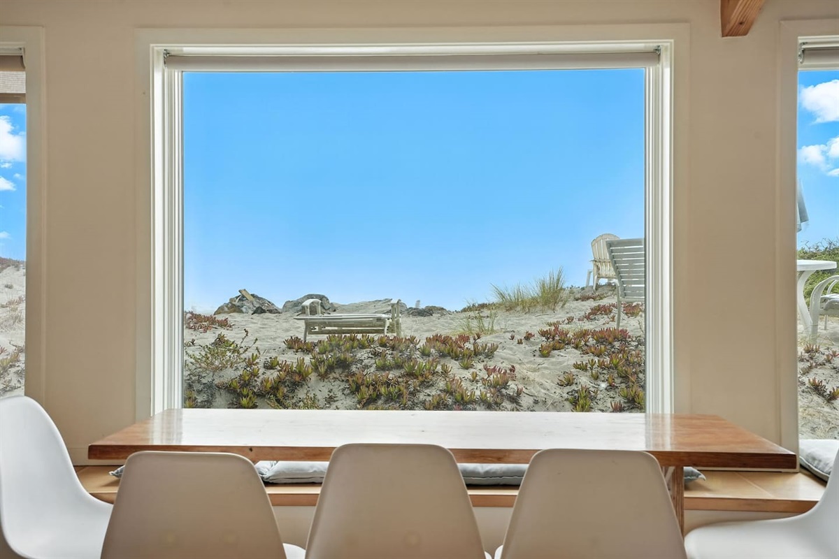 - Dining area with stylish picture window overlooking the sandy dunes  
- Wooden table with white chairs provides the perfect setting for any meal  
- Unobstructed views create a serene and picturesque dining experience  