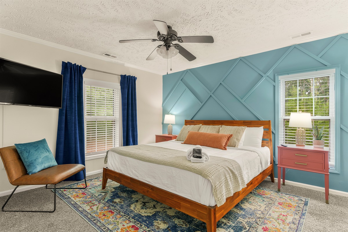 ⛰️ Sleep in style in this cool and cozy king bedroom, complete with custom mountain woodwork and playful pops of blue and pink.