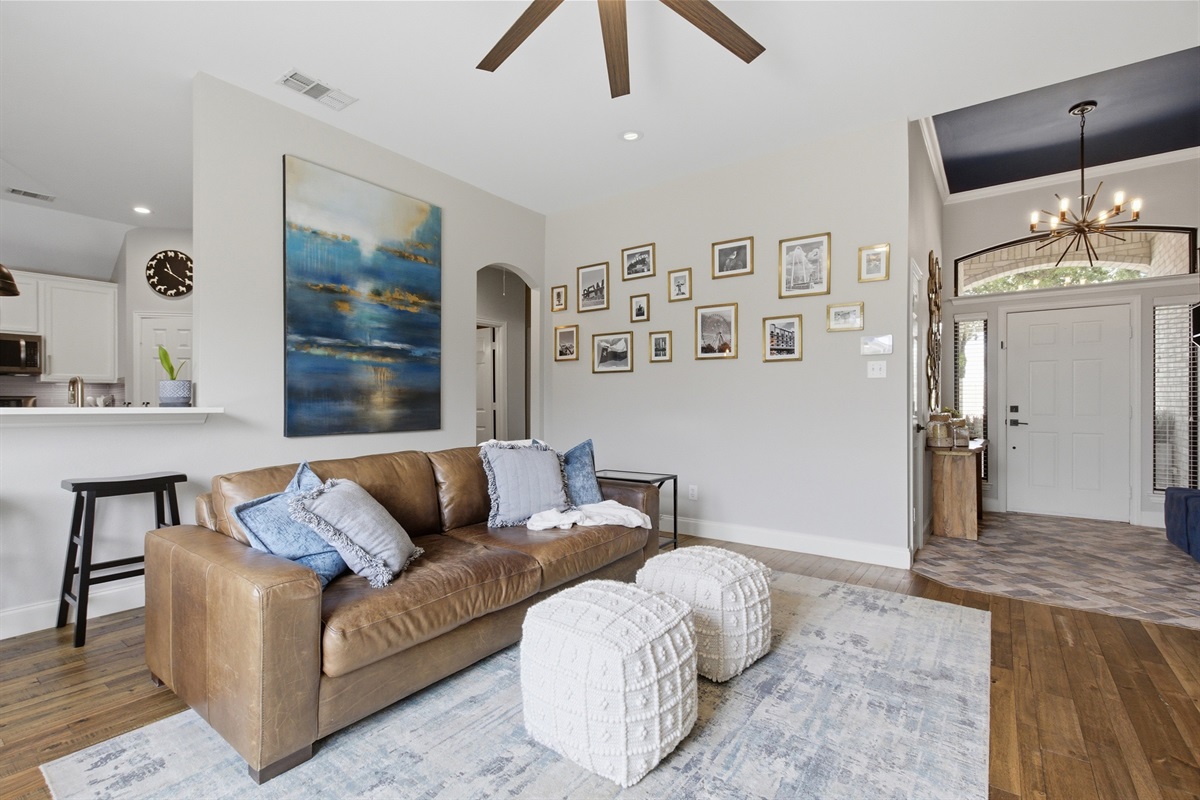 Living Room opening to the Dining and Kitchen for easy family flow. Plush sofa, ottomans, and an oversized ceiling fan keep things comfortable.
