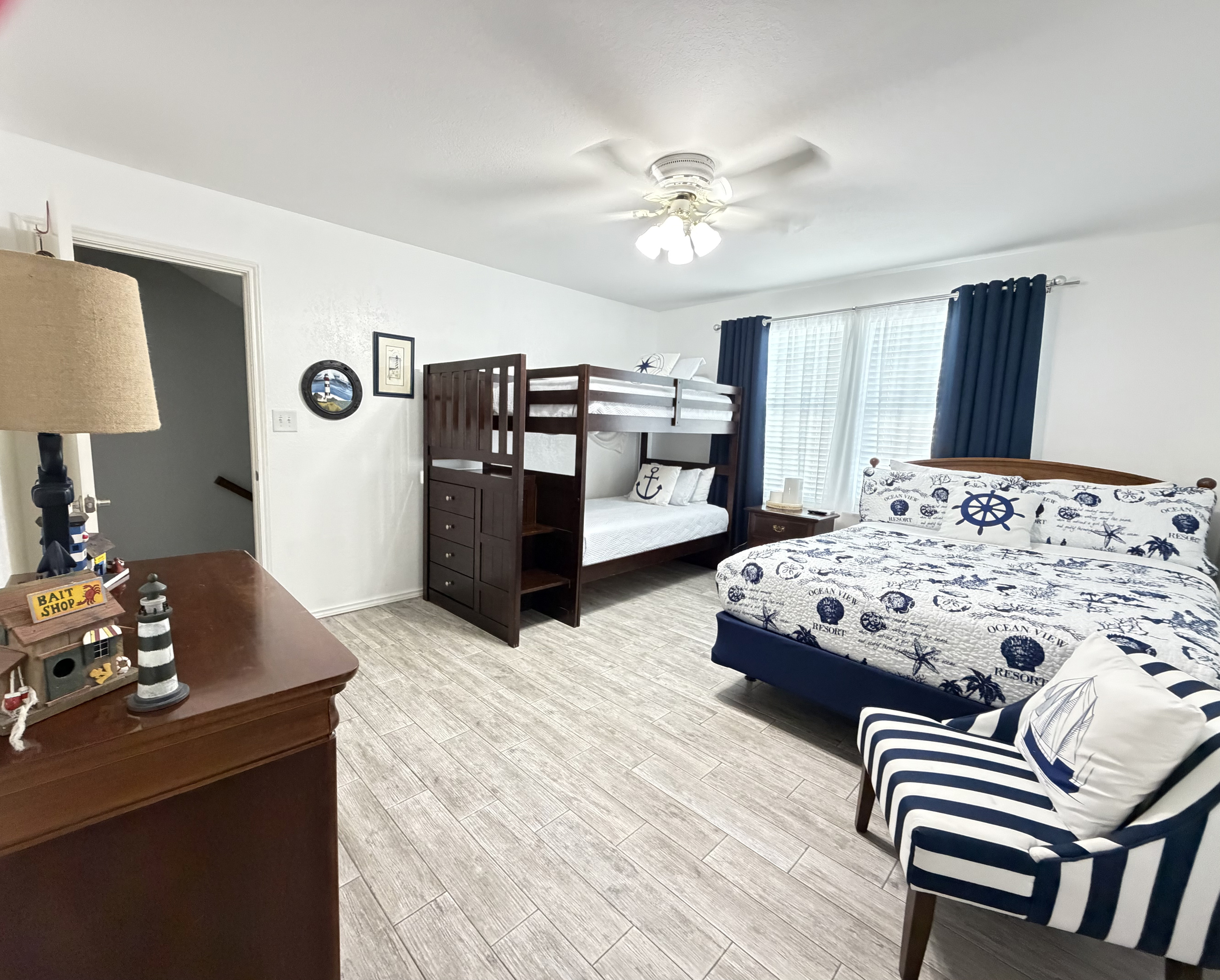 Relax in this charming coastal bedroom featuring two comfortable beds, crisp nautical-inspired linens, and classic navy-and-white accents.  Queen bed and twin bunk beds.