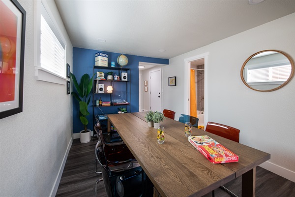 large and spacious dining table and area looking towards back of house and bathroom entrance, and further back towards the laundry room and game room entrance
