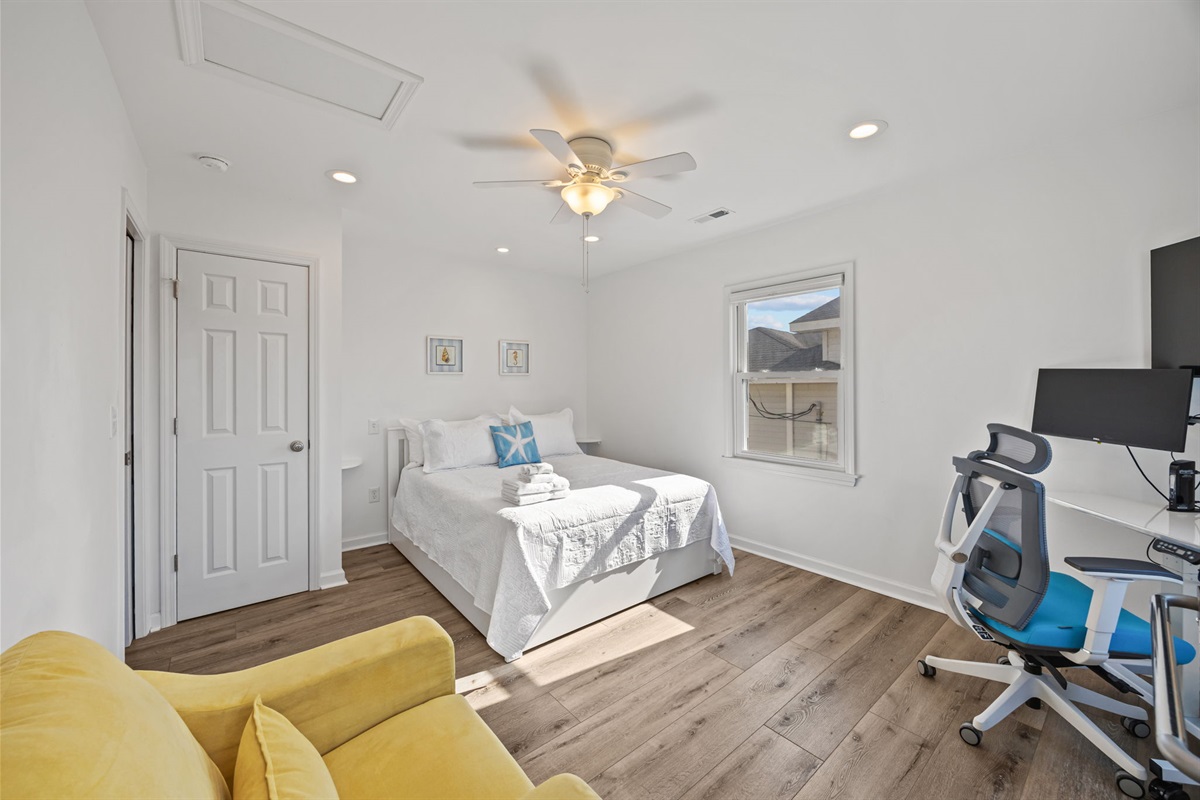 Calm, bright retreat with a comfortable bed, ceiling fan, and dedicated workspace for remote-friendly stays