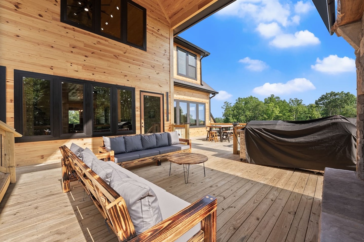 Relax and socialize in the outdoor lounge area complete with cozy seating, a rustic wood coffee table, and seamless access to the expansive deck.