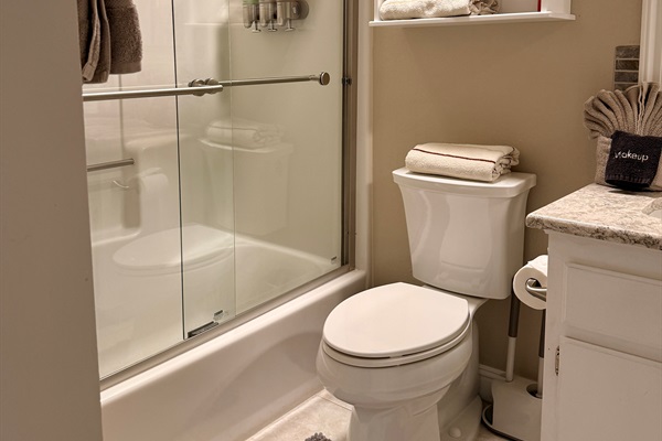 Upstairs hall bath with full shower and bathtub. Stocked with towels, hand towels, wash cloths, labeled makeup removing towels, extra toothbrushes with mini toothpaste, razors, floss, Q-tips, feminine hygiene products, a hair dryer, and a folding stool.