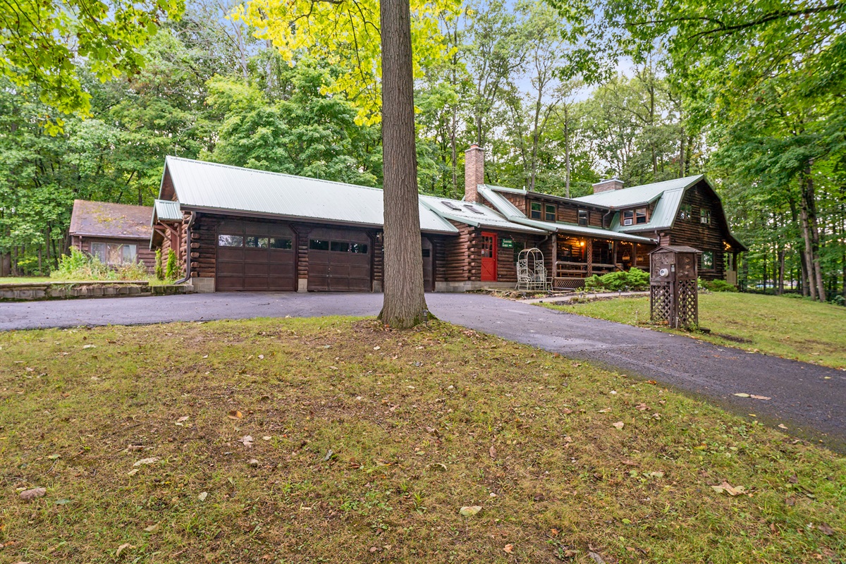 Charming log cabin retreat with rustic details, inviting front porch, and serene wooded surroundings—ideal for a cozy getaway.