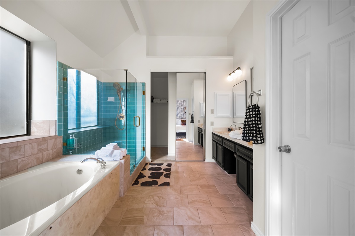 Elegant primary bedroom's bath retreat with tub, shower, and double vanity.