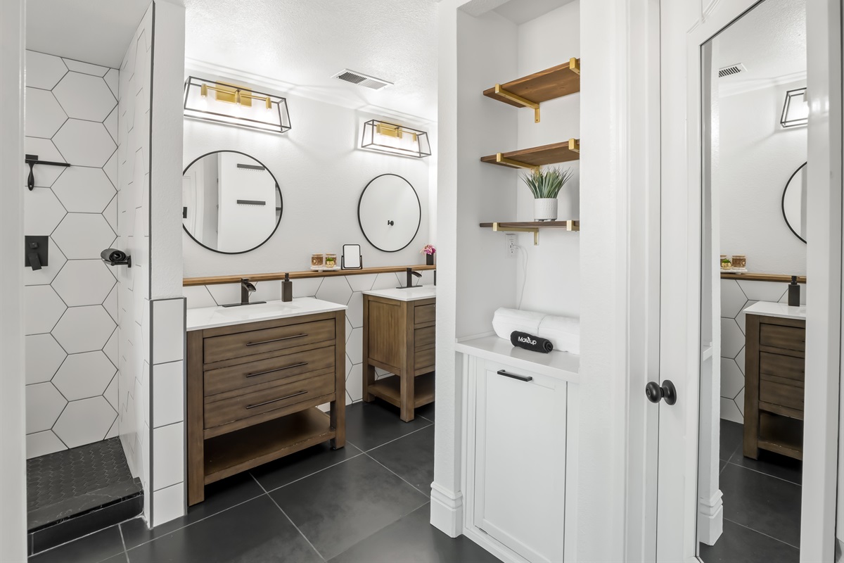 Bright and beautifully updated en-suite bathroom featuring dual vanities, modern fixtures, and a sleek walk-in shower with statement tile. Thoughtful shelving and ample counter space make it easy to settle in and feel right at home.