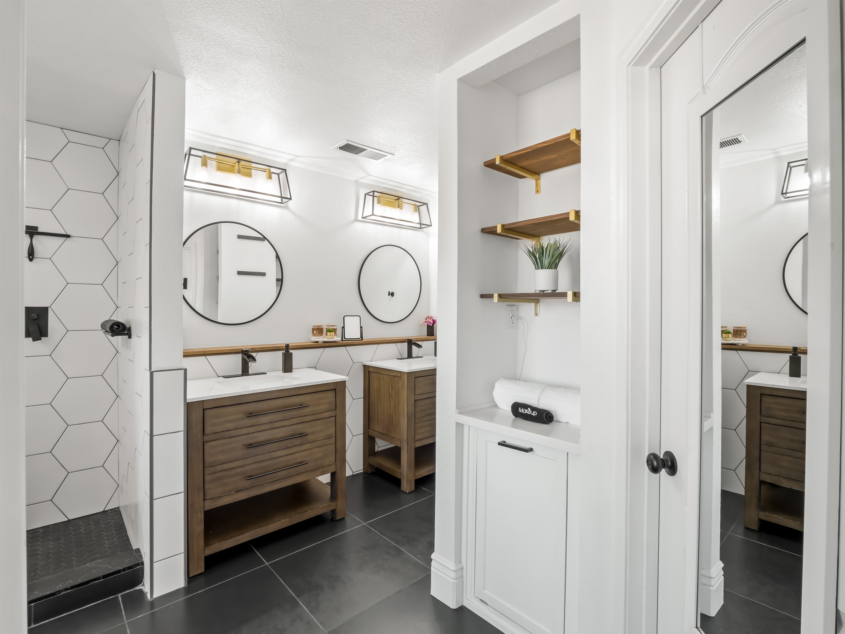 Bright and beautifully updated en-suite bathroom featuring dual vanities, modern fixtures, and a sleek walk-in shower with statement tile. Thoughtful shelving and ample counter space make it easy to settle in and feel right at home.