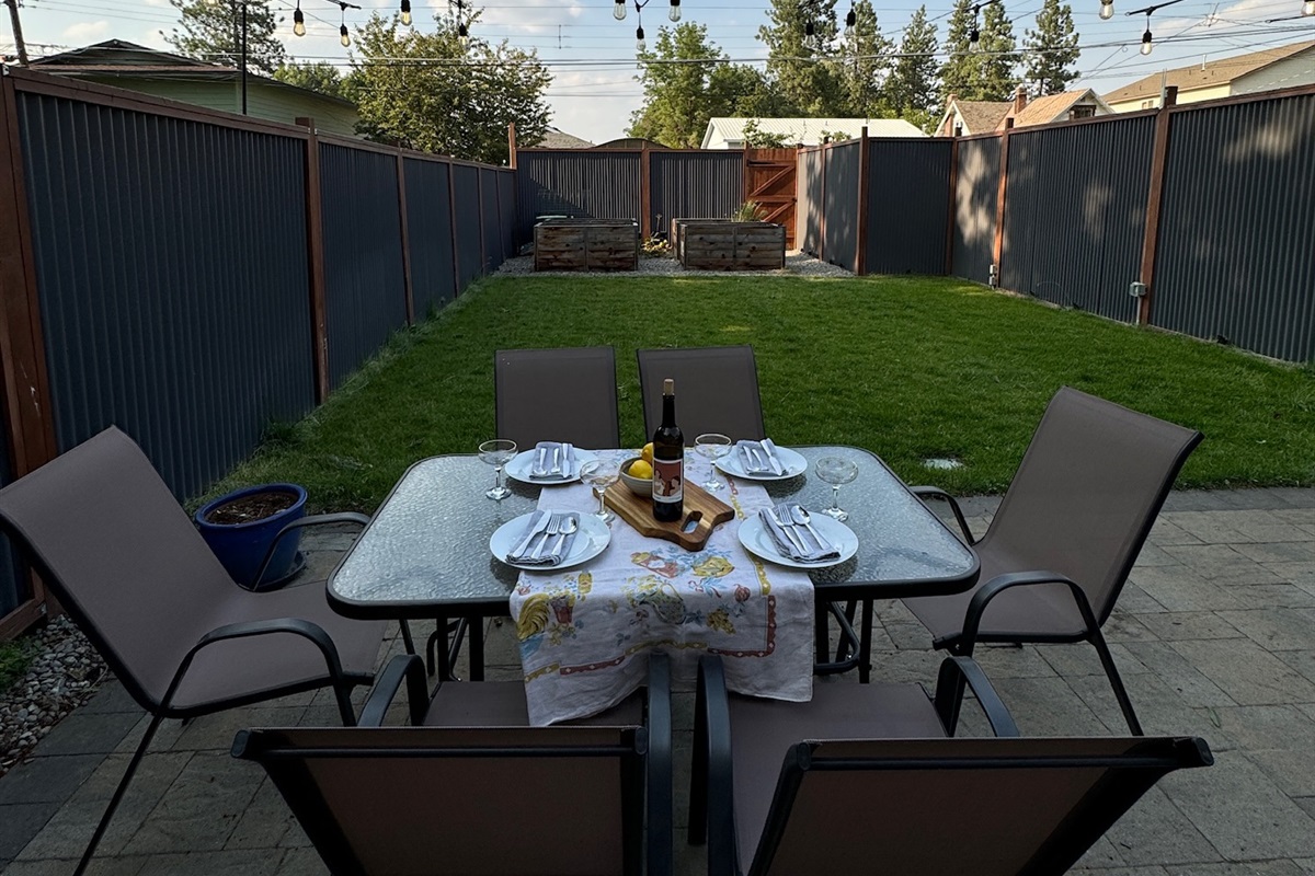 Private fenced backyard with string lights and patio dining