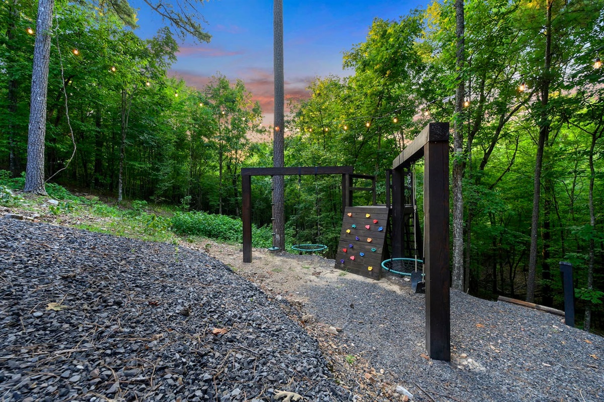 Custom built play toy features a rock wall, cargo net and two swing beams.