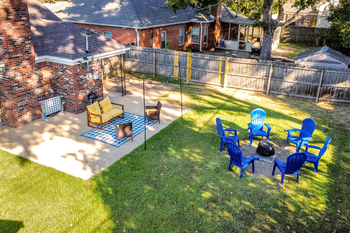 Fenced backyard with string-lit patio, fire pit, and electric grill.