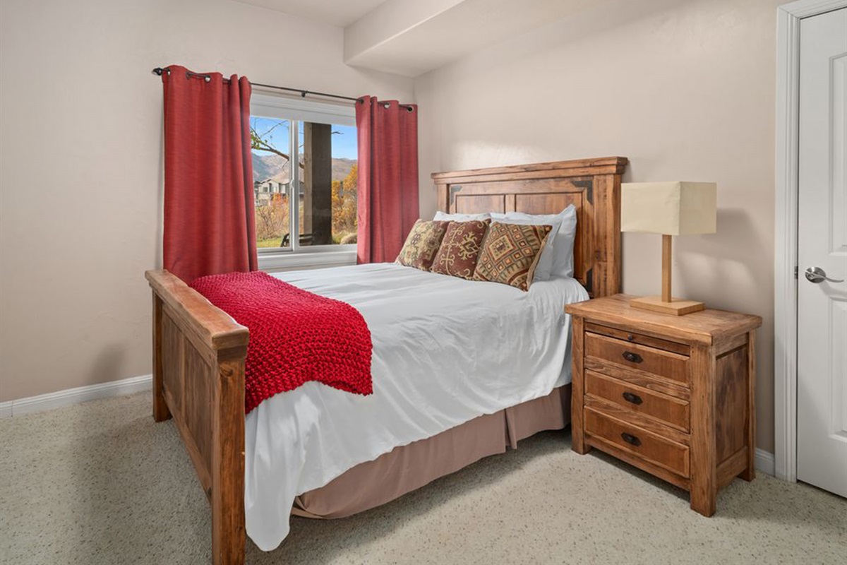 An inviting bedroom with a queen bed, warm décor, and natural light.