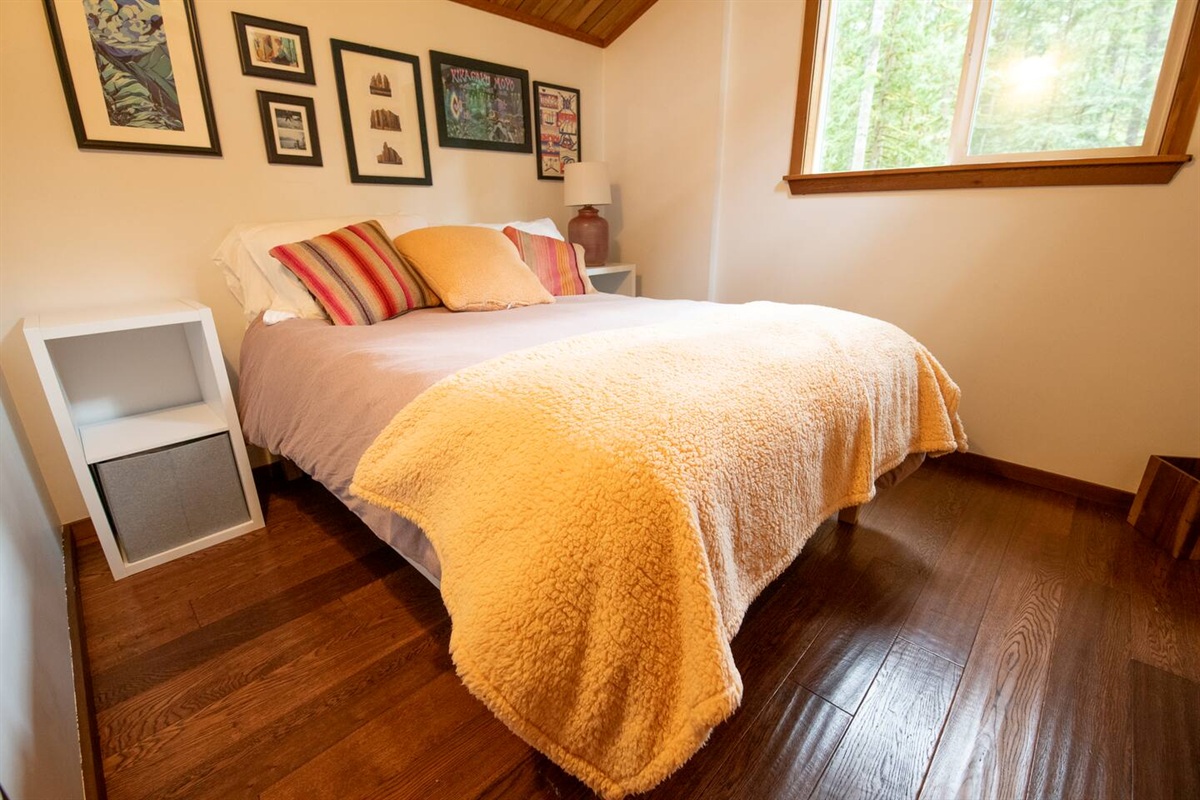 2nd Bedroom with a full-sized bed, two nightstands with lamps, and a view into the cedar forest backyard.  