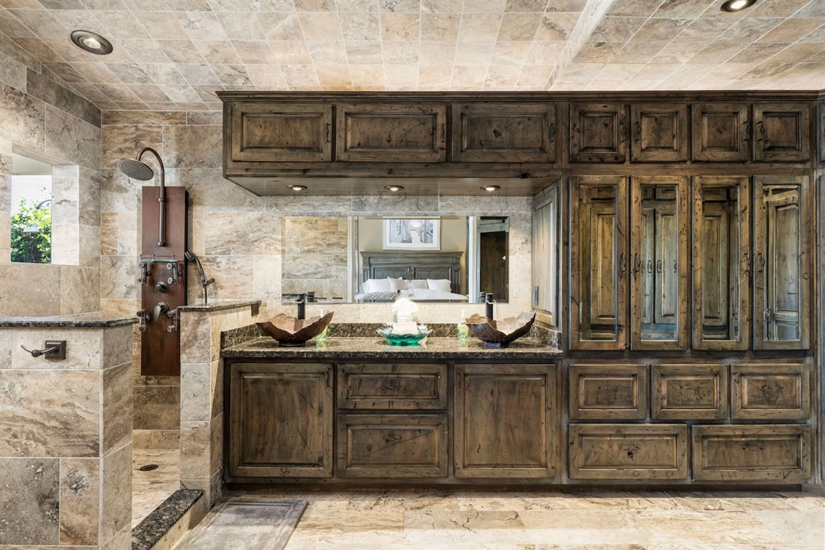 Step into the primary ensuite and feel the stress melt away — floor-to-ceiling travertine stone, dual vessel sinks, and rich wood cabinetry create a spa-like retreat you'll never want to leave.