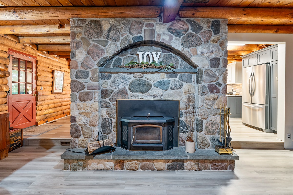 Rustic charm meets comfort with a stunning stone fireplace, warm wood interiors, and inviting leather couches, creating the ultimate cabin retreat atmosphere.