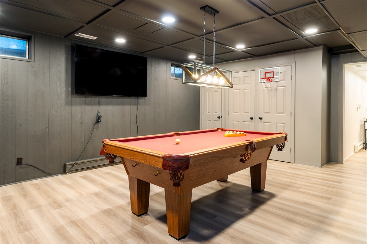 Rack ’em up and enjoy friendly competition on the classic red felt pool table, set under stylish lighting.