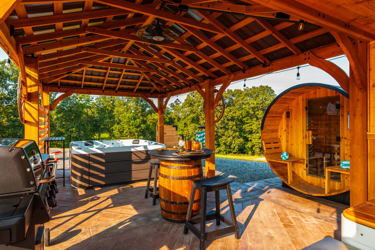 Private outdoor pavilion featuring the hot tub, barrel sauna, grill area, and peaceful wooded views.